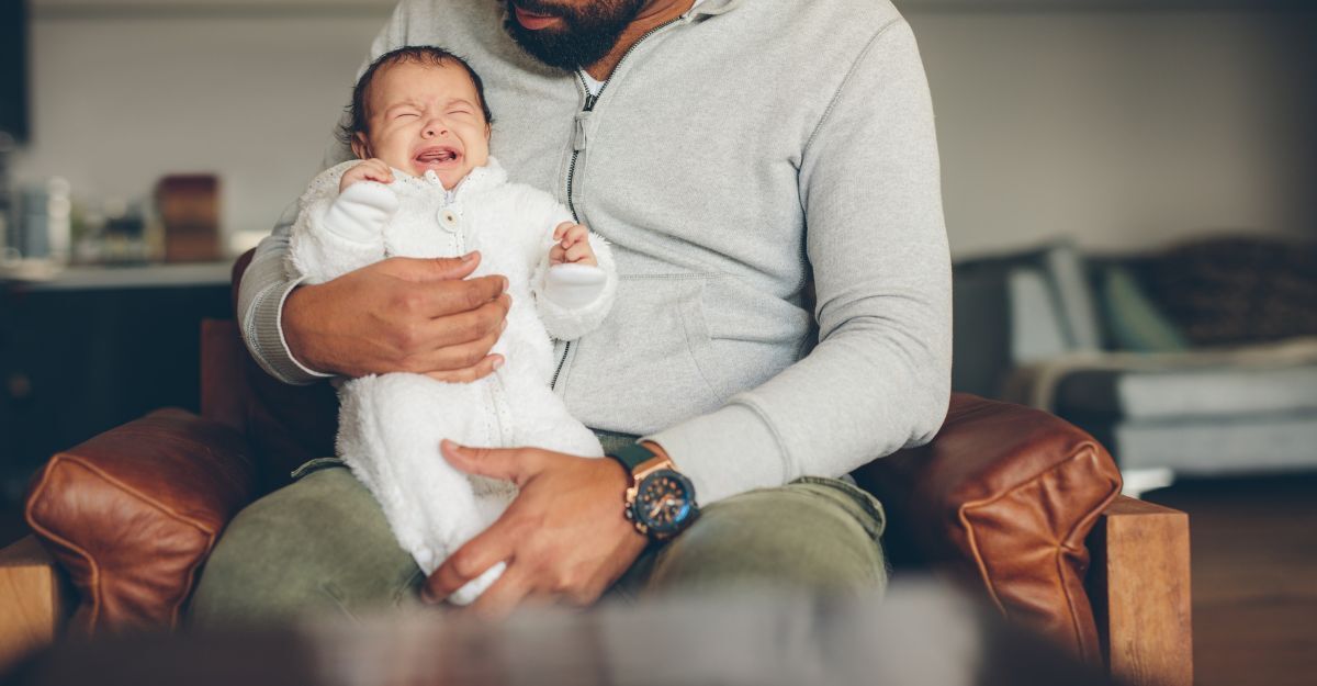 Un padre tiene in braccio un neonato che piange