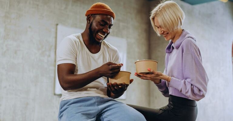 Un uomo e una donna mangiano insieme una poke in palestra