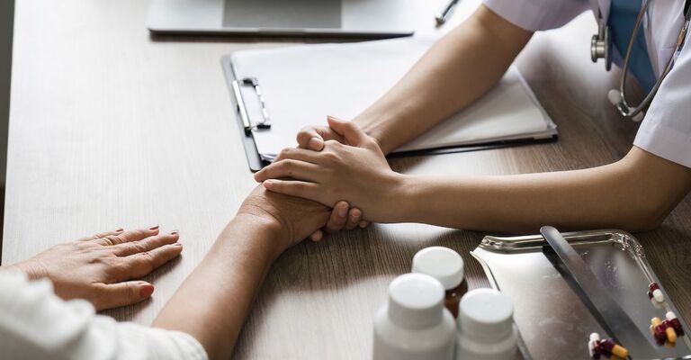 Un medico che tiene le mani del paziente