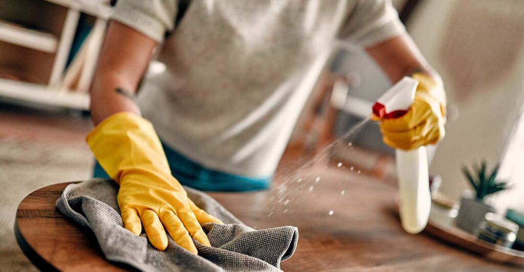 Una persona che pulisce la superficie di un tavolino