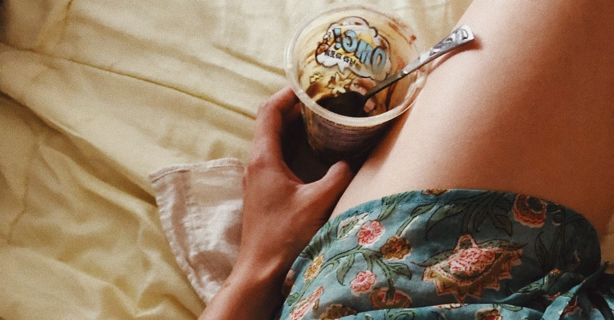 Una ragazza sdraiata a letto ha appena finito una vaschetta di yogurt