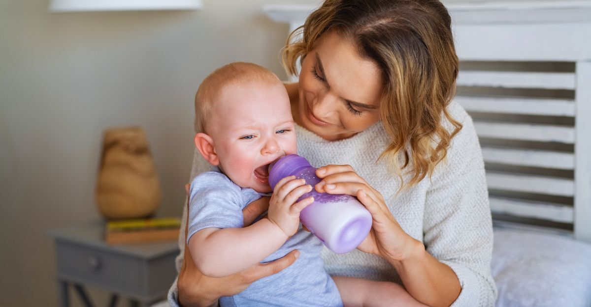 Neonato piange con il biberon in bocca mentre la madre lo aiuta a bere
