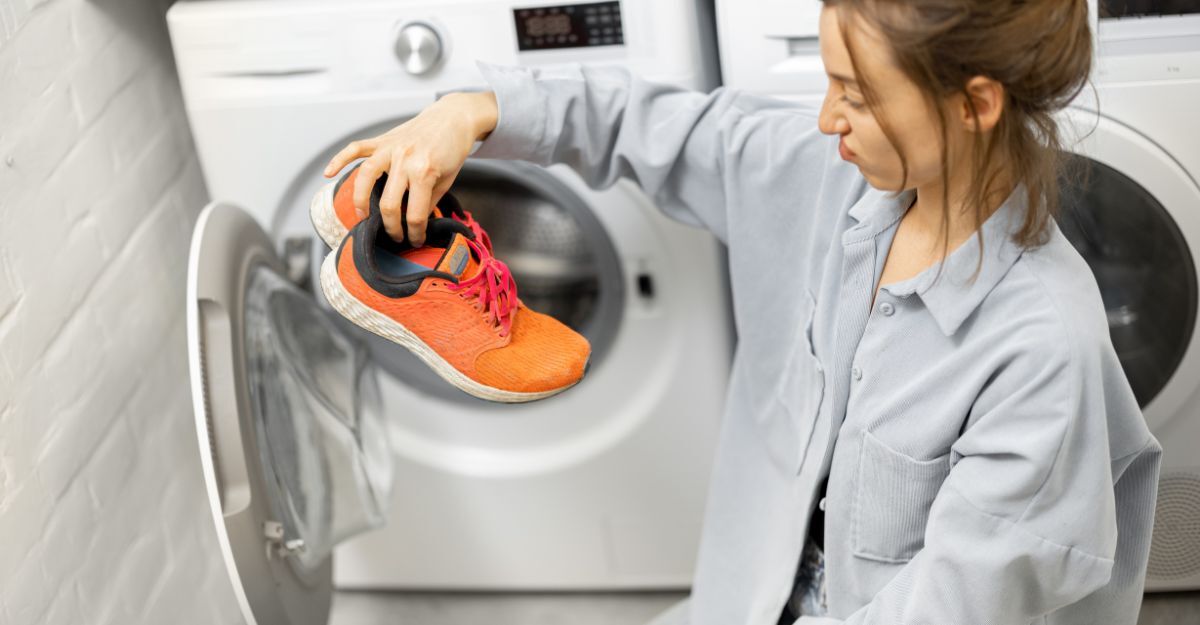 Una ragazza tiene in mano delle scarpe davanti ad una lavatrice aperta