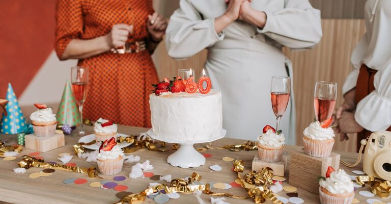 tavola imbandita a festa, con dolci e torta con candelina 60 anni