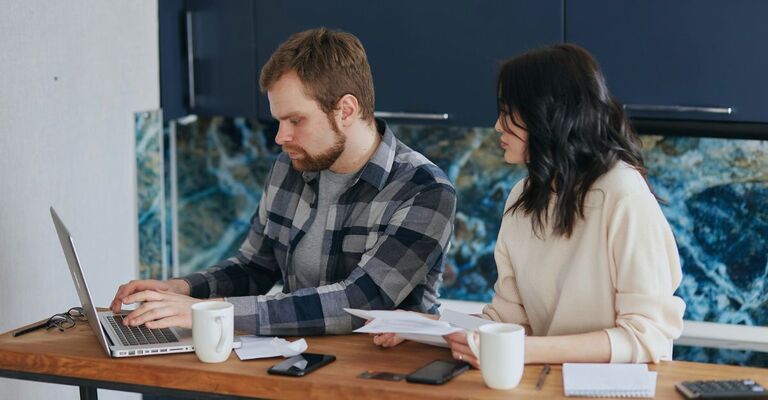 Coppia giovane che controlla insieme qualcosa al PC in cucina
