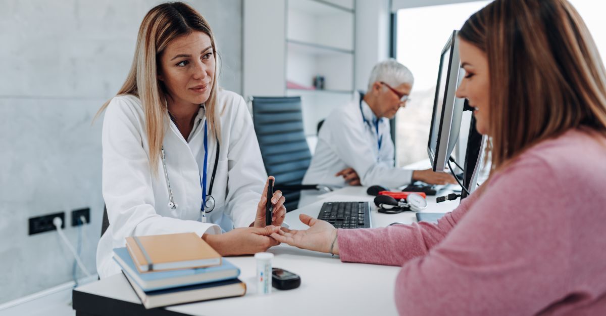 Dottoressa in uno studio medico che misura la glicemia a una sua paziente seduta di fronte a lei