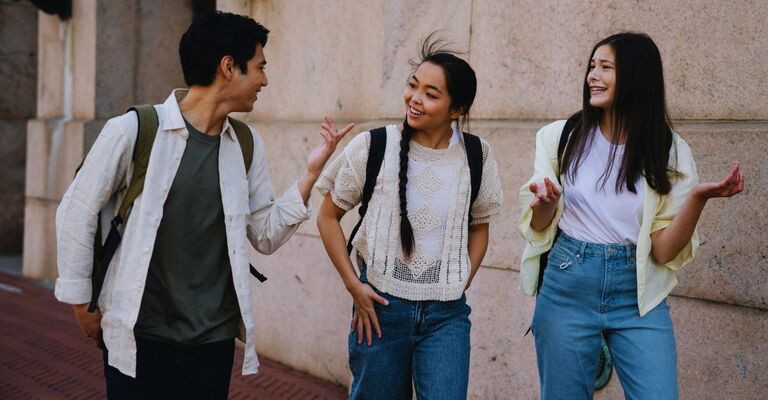 Un gruppo di amici composto da un ragazzo e due ragazza che chiacchierano mentre tornano da scuola