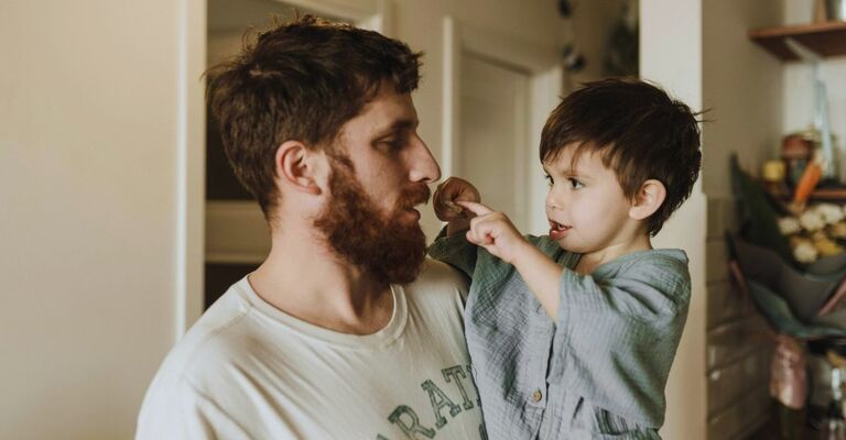 Giovane papà con in braccio suo figlio piccolo che interagisce con lui