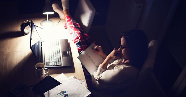 Una ragazza sveglia di notte che legge e guarda il computer