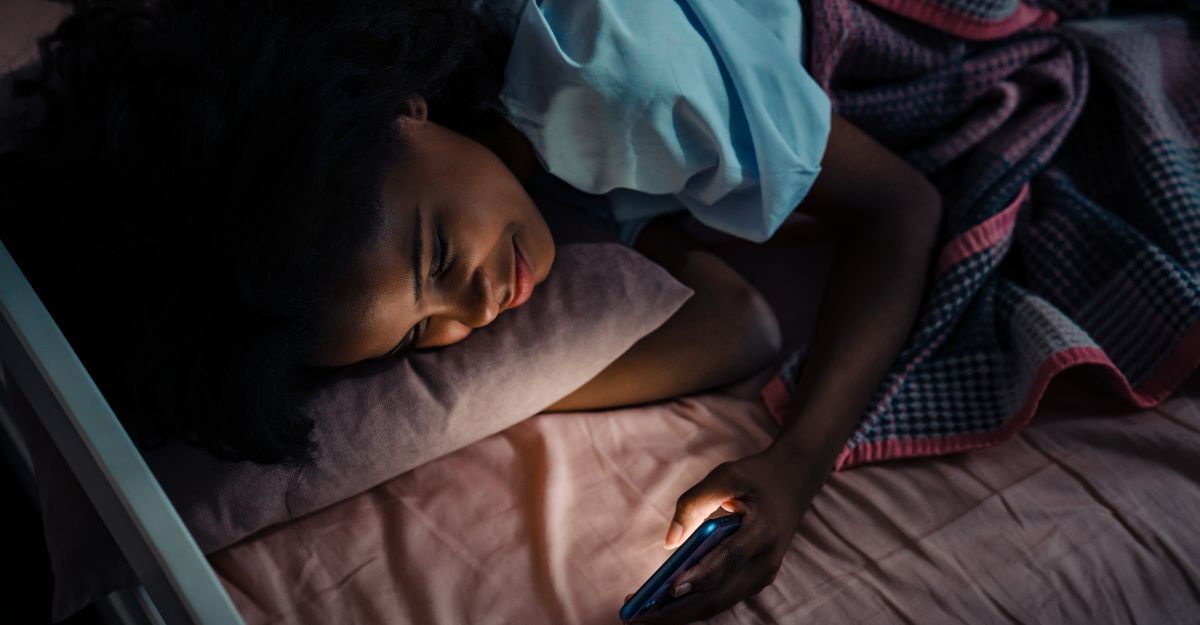 Una ragazza a letto di notte che guarda il telefono