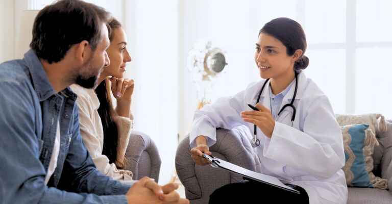 Ginecologa che parla dei risultati dei test con una coppia seduta affianco a lei