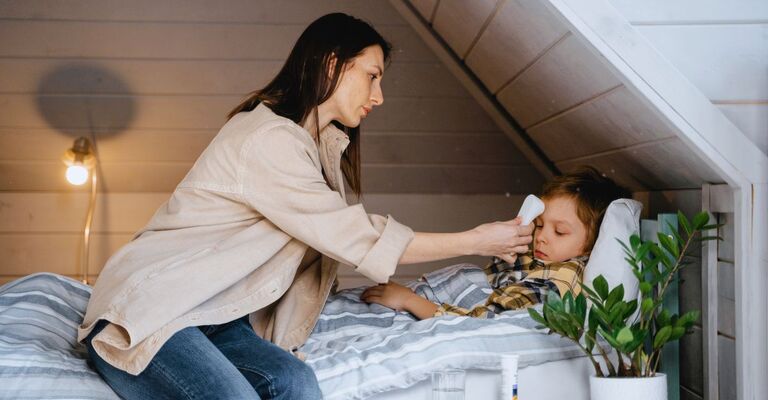 Una madre che accudisce il figlio a letto