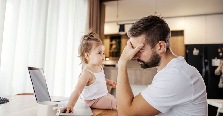 papà stanco lavora la pc e si prende cura di una bimba