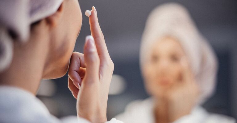 Una donna si mette una crema nel viso