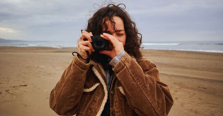 Ragazza con macchina fotografica che fotografa al mare