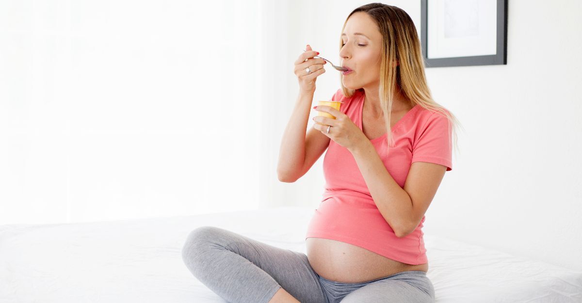 Una donna in gravidanza che mangia lo yogurt