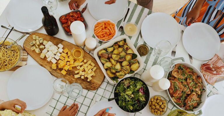 Menù di Pasquetta: ricette sfiziose e idee per un pranzo (non solo all’aperto) indimenticabile Tavolata con pietanze miste e vino e mani di persone che si servono