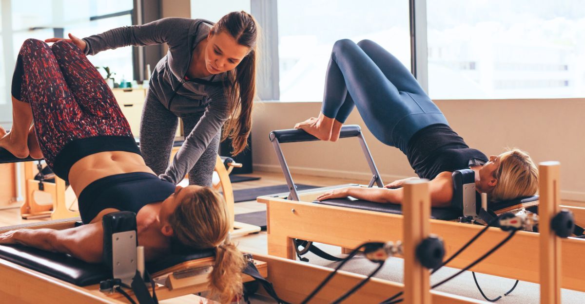 Due donne durante una lezione di pilates reformer che vengono seguite dall'insegnante