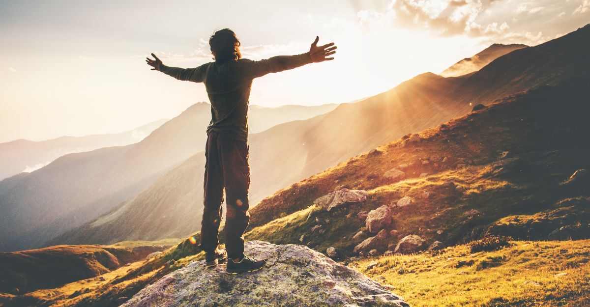 Un ragazzo a braccia aperte davanti ad una montagna