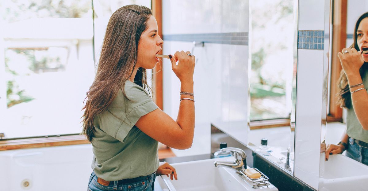 Ragazza che si lava i denti in bagno davanti allo specchio e al lavandino