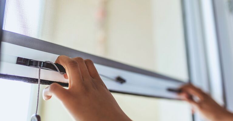 Mani che tirano su una zanzariera