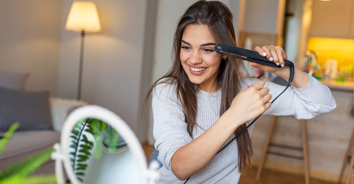 ragazza si liscia i capelli con la piastra