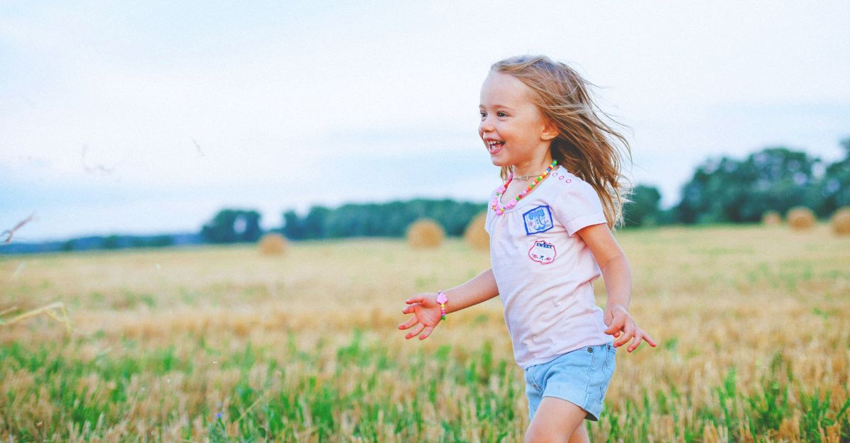 Bambina piccola che corre spensierata in un campo
