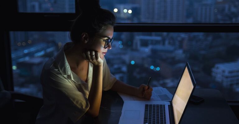Una ragazza che lavora a computer di notte