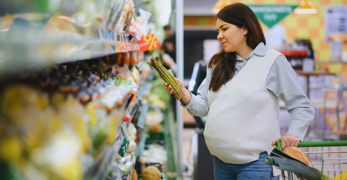 Donna in un supermercato che tiene in mano un mazzo di asparagi