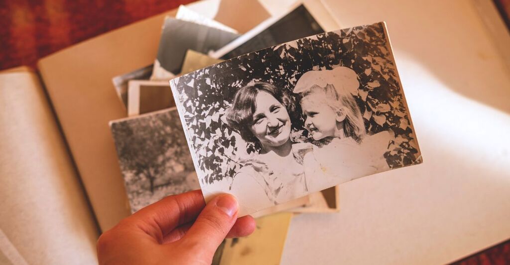 Mano che tiene una foto sopra un album di fotografie