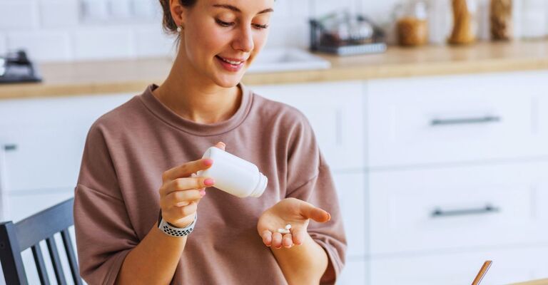 Ragazza che versa delle pillole sulla mano