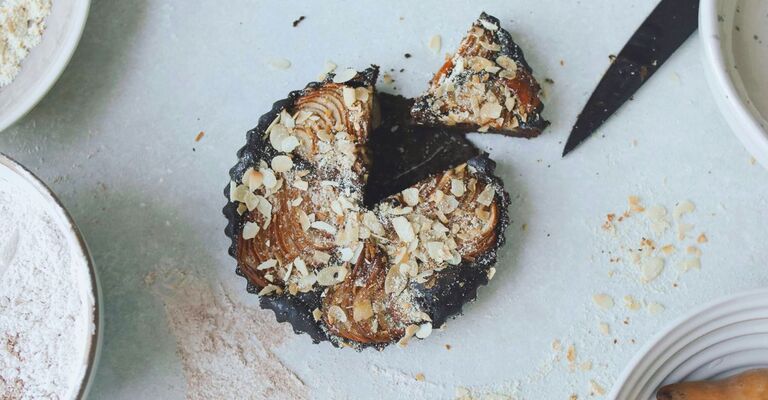 Foto di una torta su un tavolo con una copertura di lamella di mandorle e un coltello accanto con il quale è stata tagliata una fetta