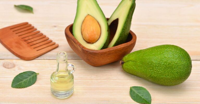 Olio di avocado, frutto di avocado e un pettine