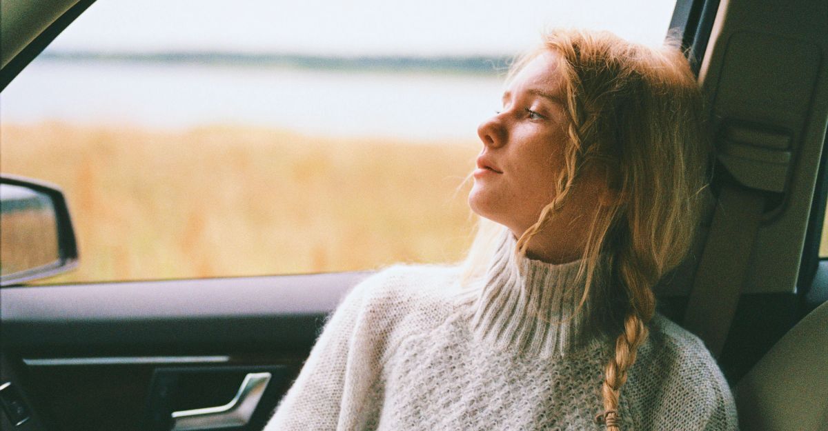 Ragazza pensierosa in macchina che guarda davanti a sé fuori dal finestrino