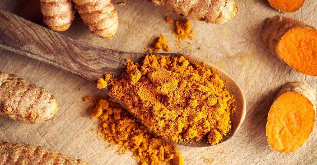 Un primo piano della curcuma macinata su un cucchiaio di legno.