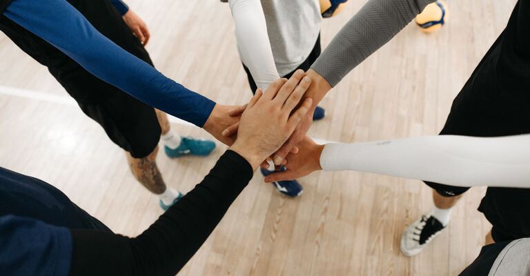 mani di persone si toccano, mimando il "uno per tutti, tutti per uno"