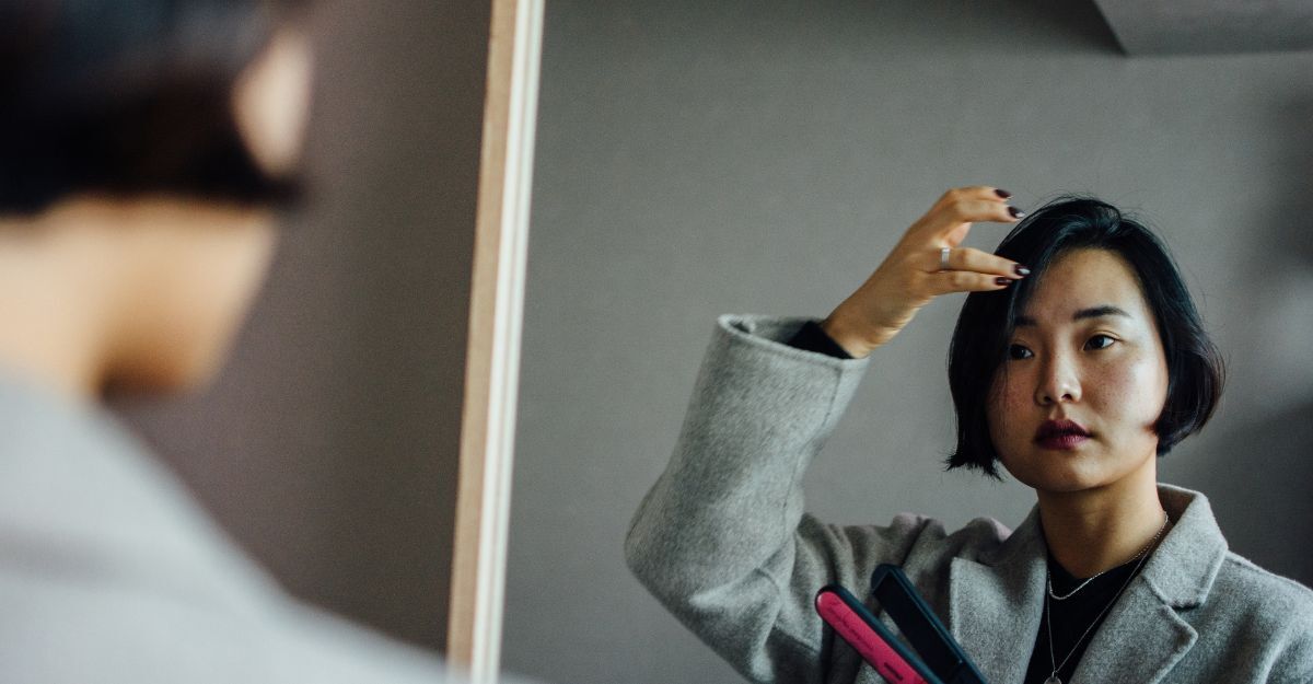 Una ragazza si piastra i capelli allo specchio