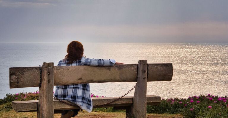 donna seduta su una panchina guarda il mare