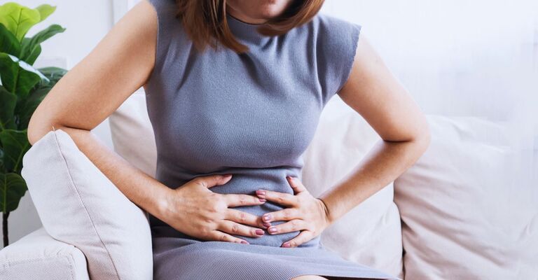 Donna che tiene le mani sul ventre mentre è dolorante