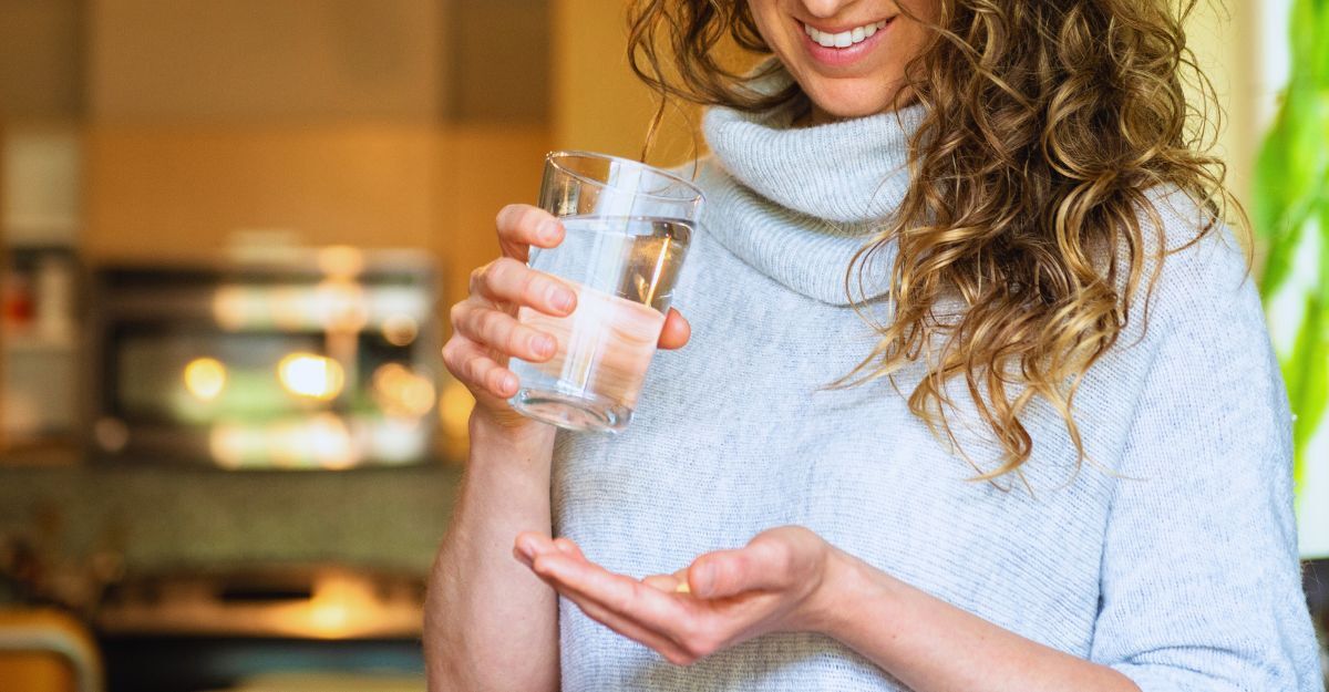 Donna assume integratori in compresse con un bicchiere d'acqua