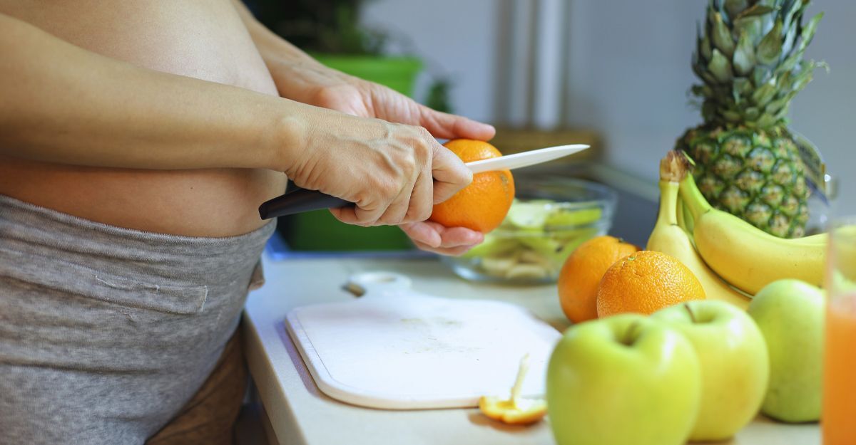 Donna in gravidanza sbuccia un'arancia