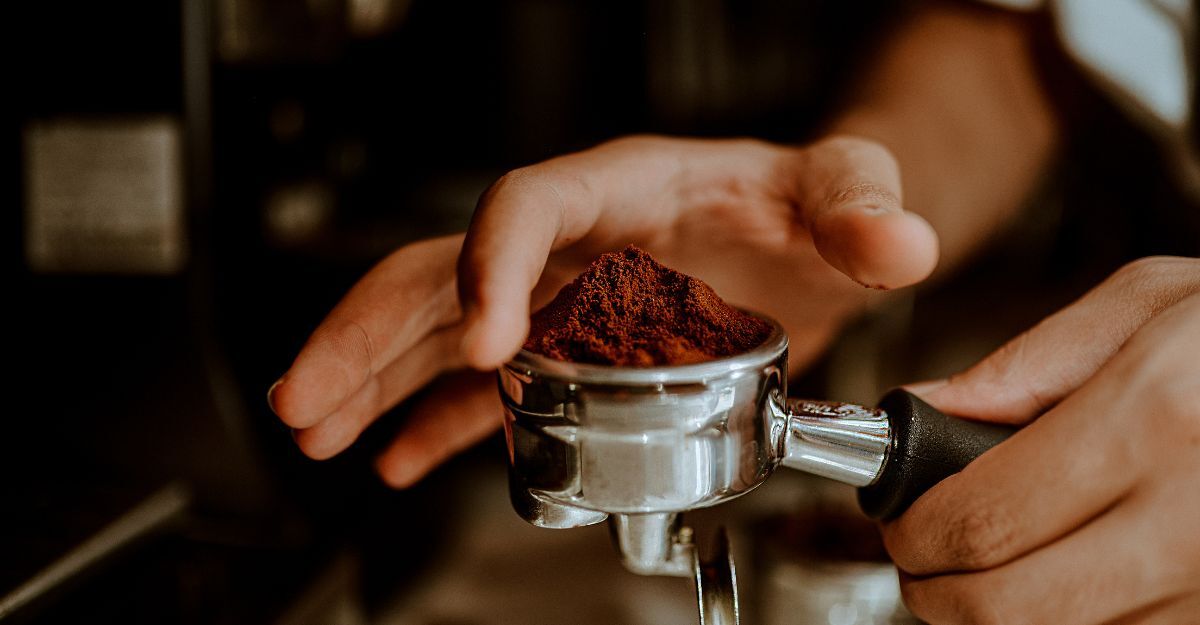 Mani di un barista mentre pressano il caffè macinato