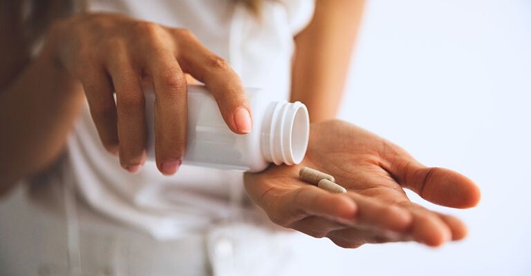 Donna tiene in pano pastiglie di integratori