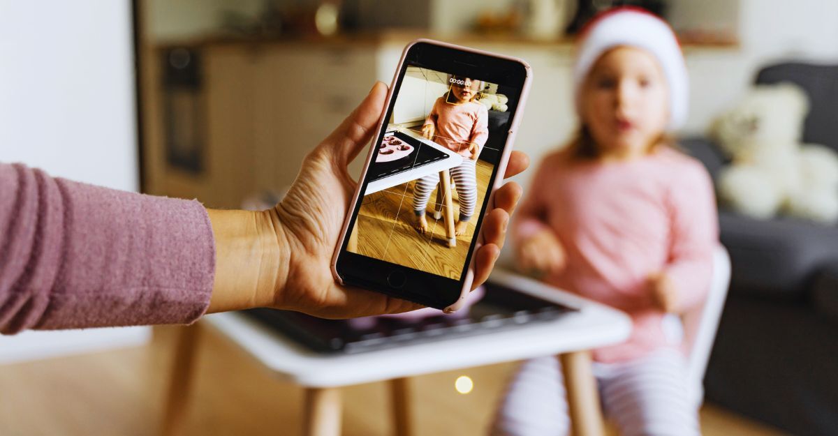 Mamma che tiene lo smartphone per inquadrare la figlia neonata sul seggiolone