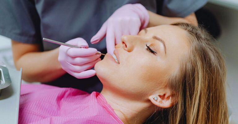 Donna sdraiata in uno studio medico sottoposta al controllo dell'igienista dentale