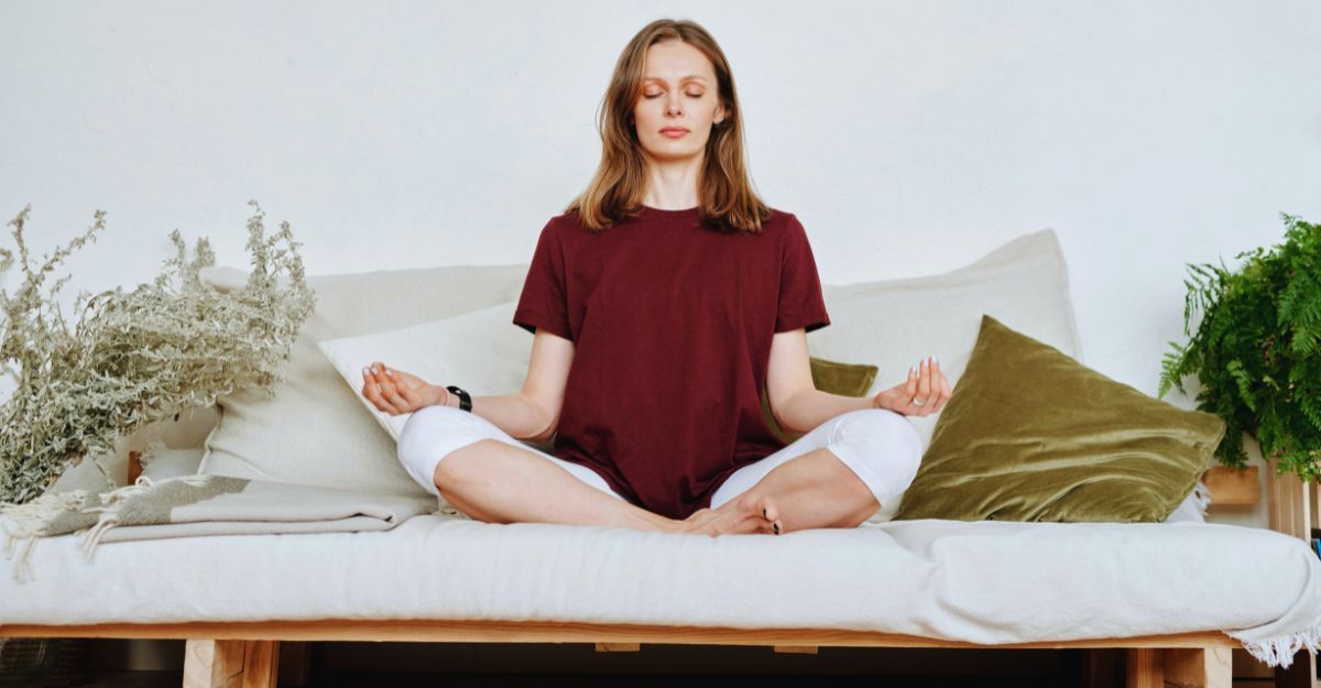 Donna sul divano che pratica meditazione a occhi chiusi