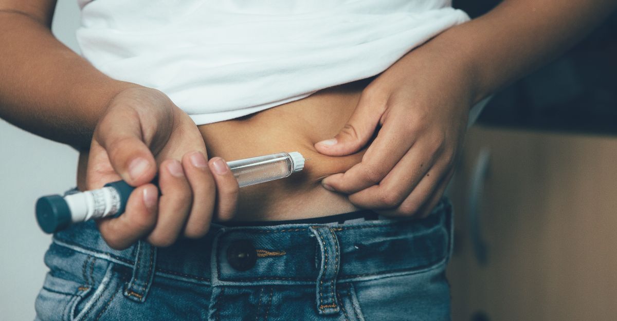 Persona si somministra insulina sull’addome con una penna iniettiva, concetto di terapia per il diabete