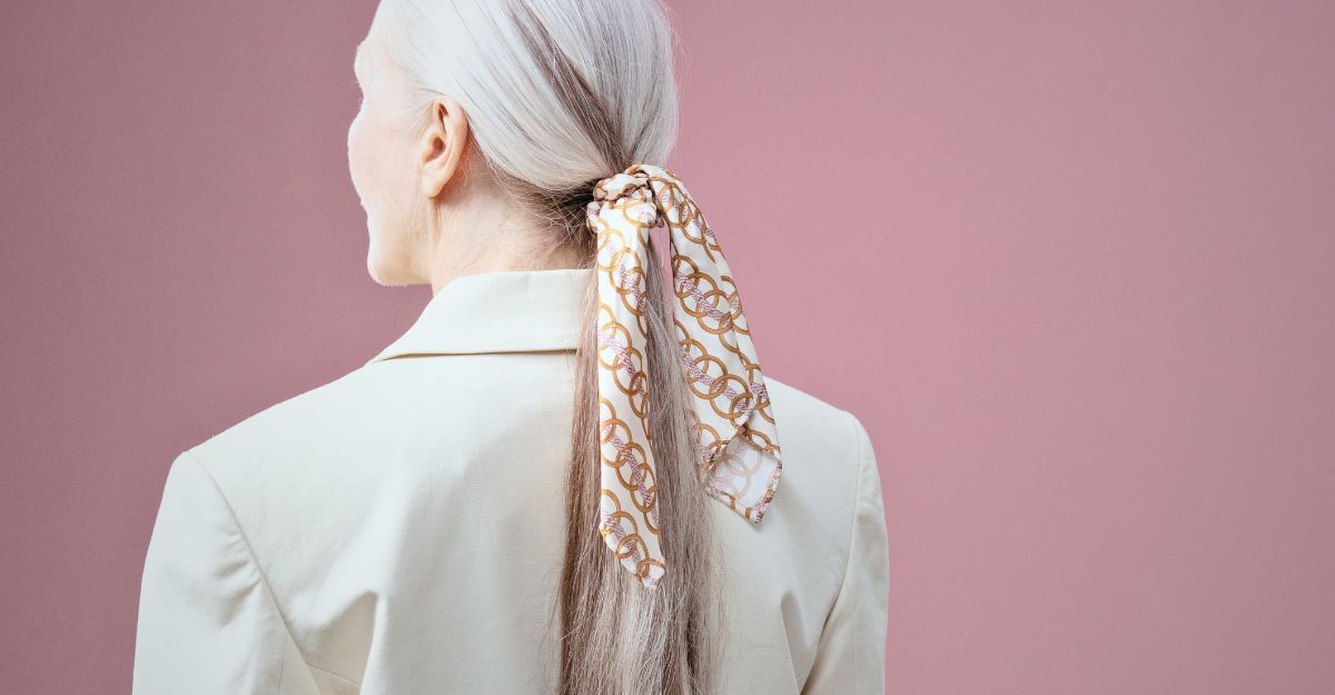 Una donna girata di schiena con i capelli grigi raccolti in un foulard