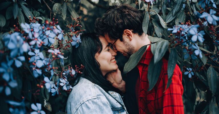 Una coppia che si bacia vicino ai fiori di una pianta