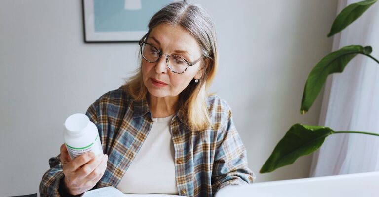 Donna over 50 che legge l'etichetta di una confezione di integratori